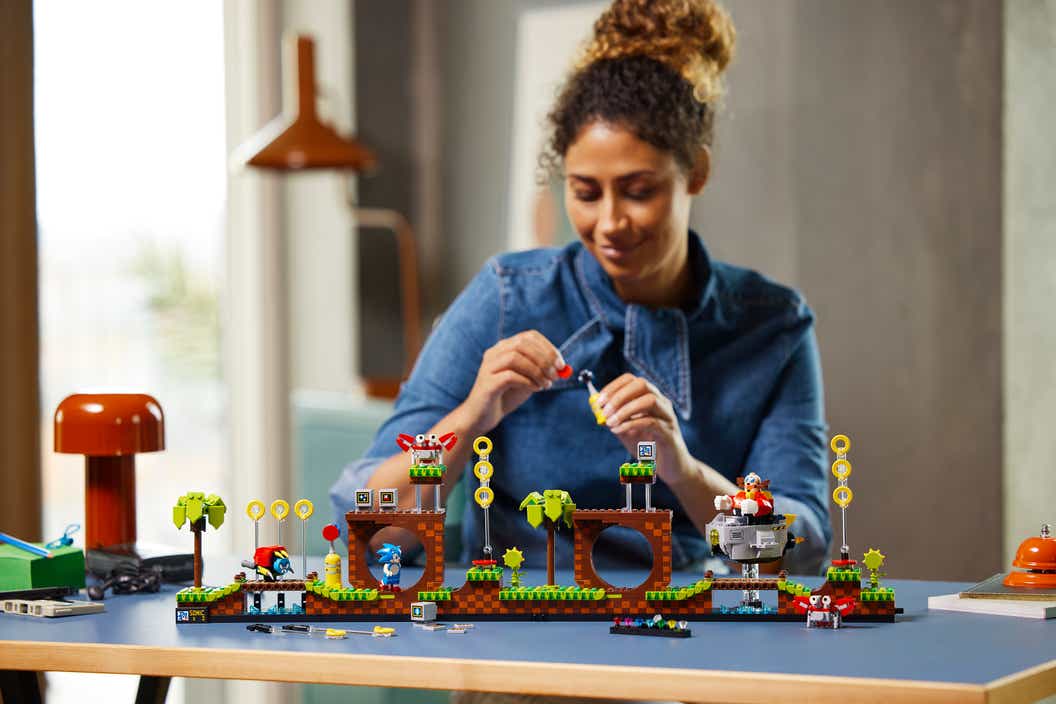 Lifestyle image of woman building LEGO Ideas Sonic the Hedgehog Green Hill Zone set