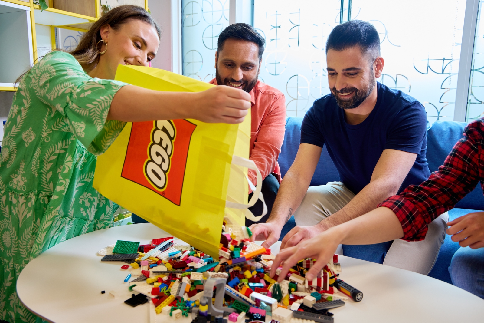 Adults building with LEGO toys — official LEGO brand lifestyle photo