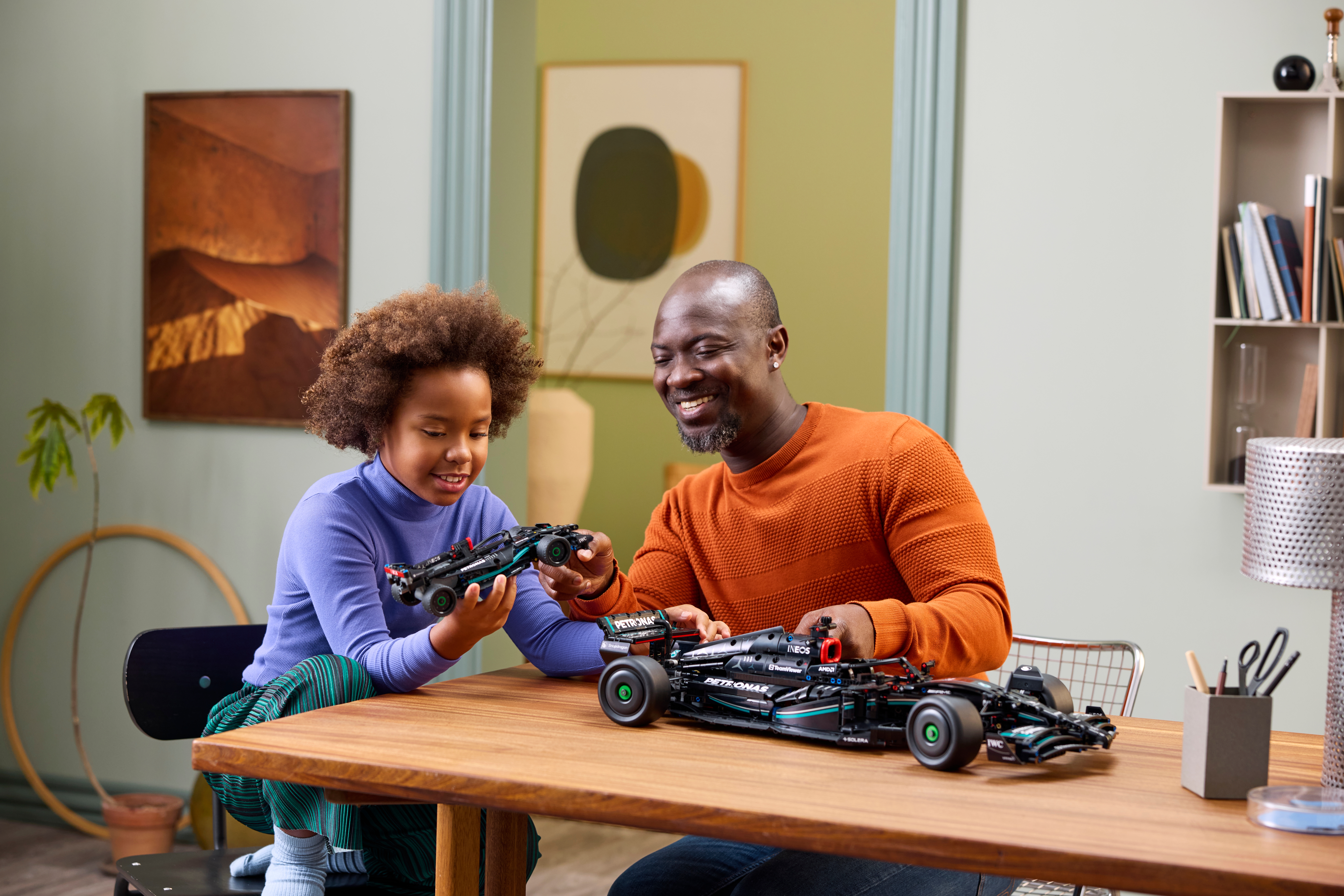 Image of a man with a orange shirt and a girl in a purple shirt looking and building the LEGO Technic 42171 car