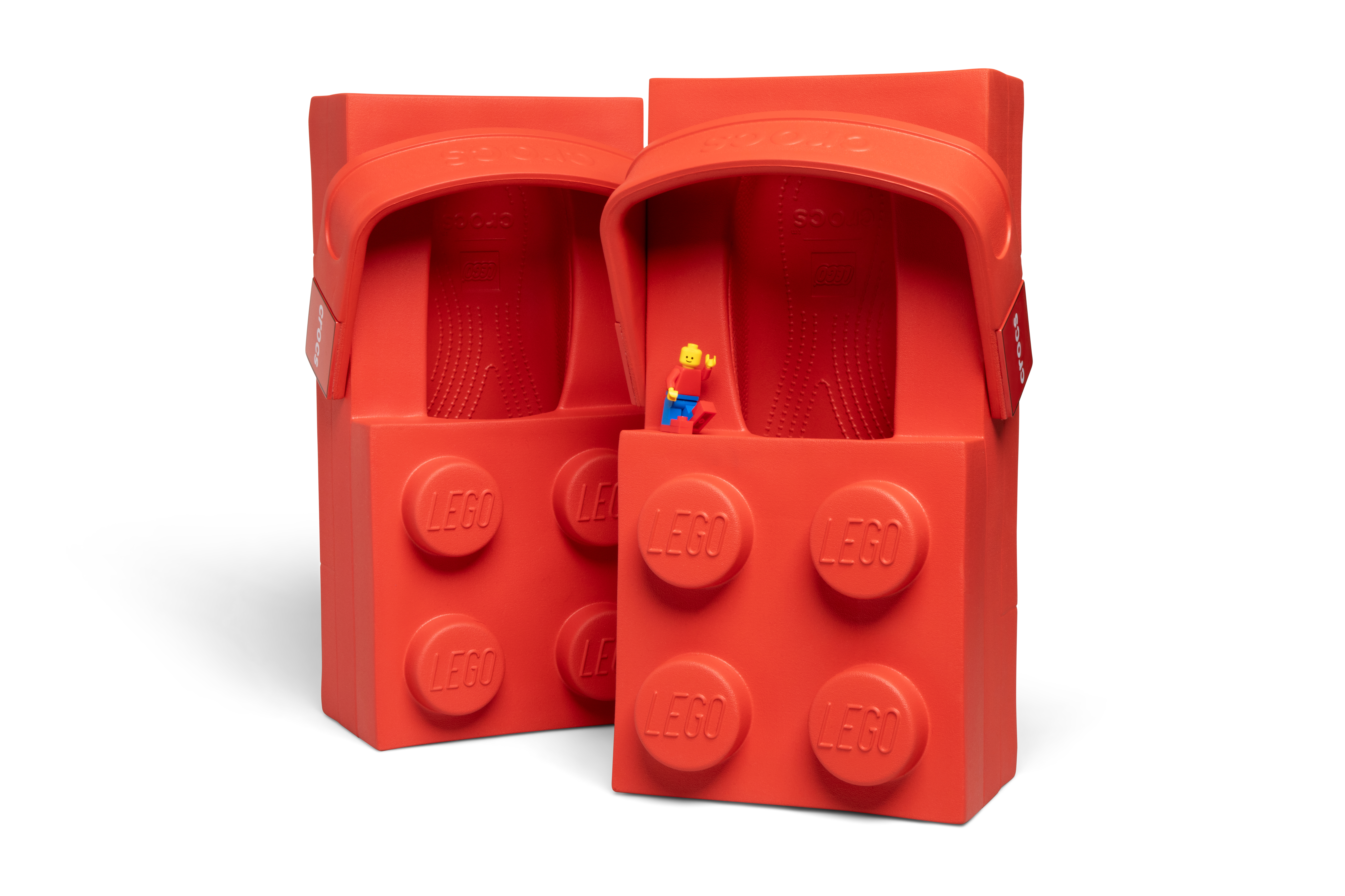 Image of the red LEGO Brick Clog shoe against a white background with the LEGO Minifigure wearing its own miniature Crocs shoes