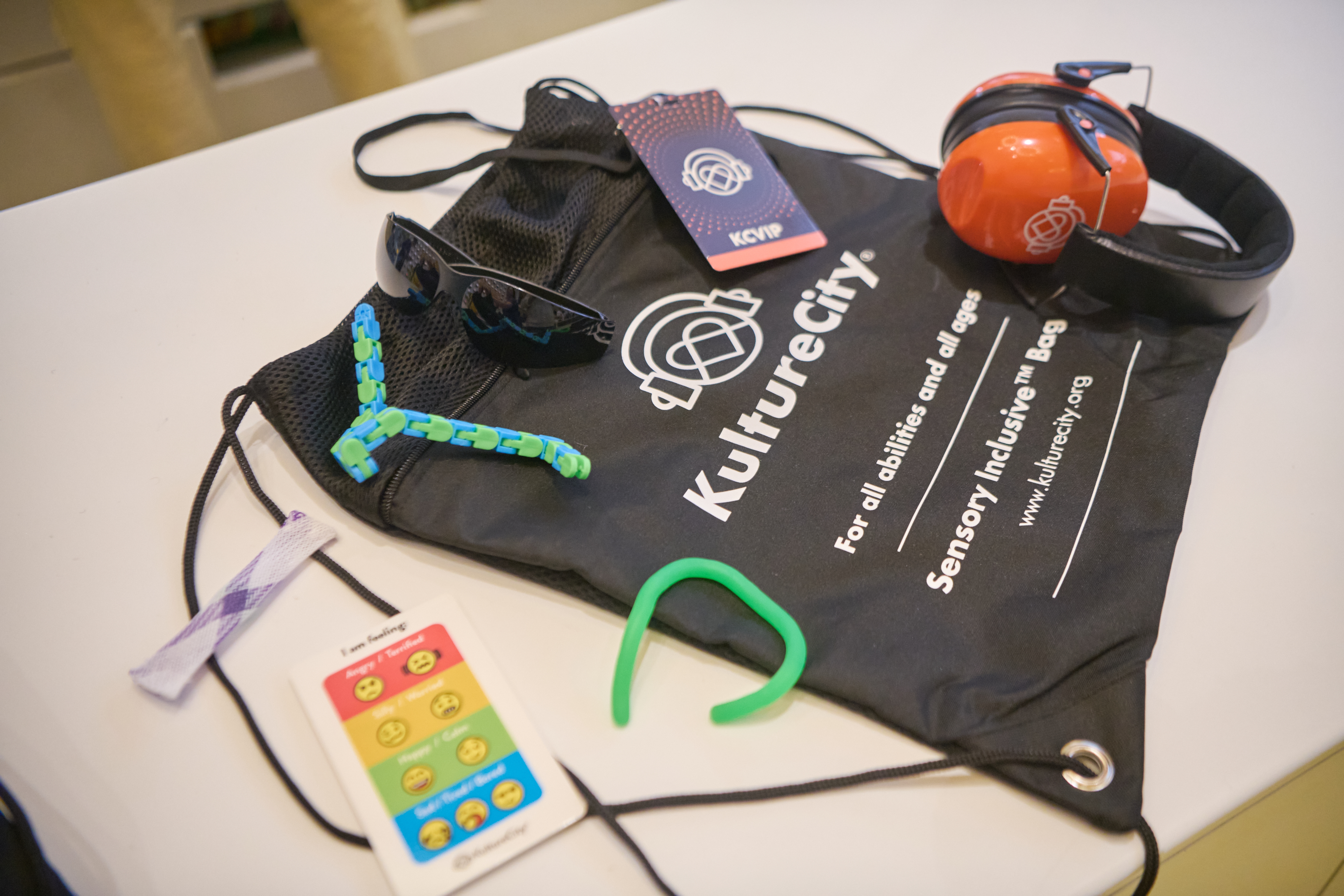 Image of the Kulture city sensory bag and what it contains including noise reducing headphones, fidget tools, visual cue cards, KultureCity branded lanyards and strobe reduction glasses