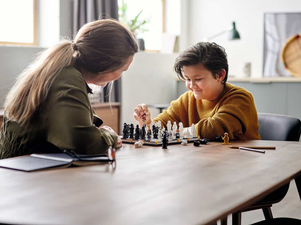 Lifestyle image of women and a boy sitting at a table playing LEGO® Harry Potter™ Hogwarts™ Wizard’s Chess