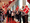 A male walking down a red carpet with colleagues either side waving Danish flags