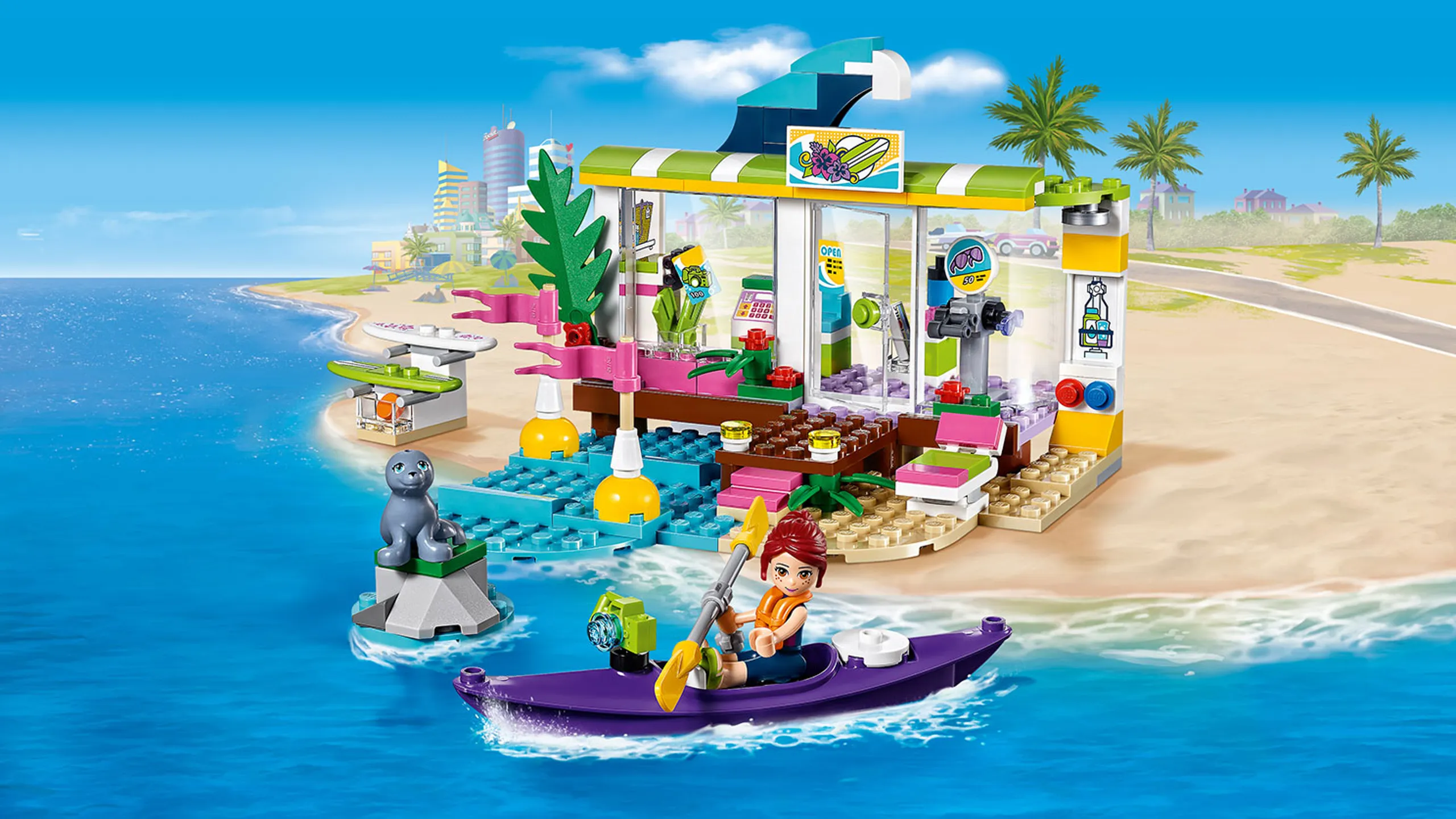 LEGO Friends - 41315 Heartlake Surf Shop - Mia paddles in her kayak in front of the Surf Shop on the beach and the seal sits on a rock in the sea near the beach.