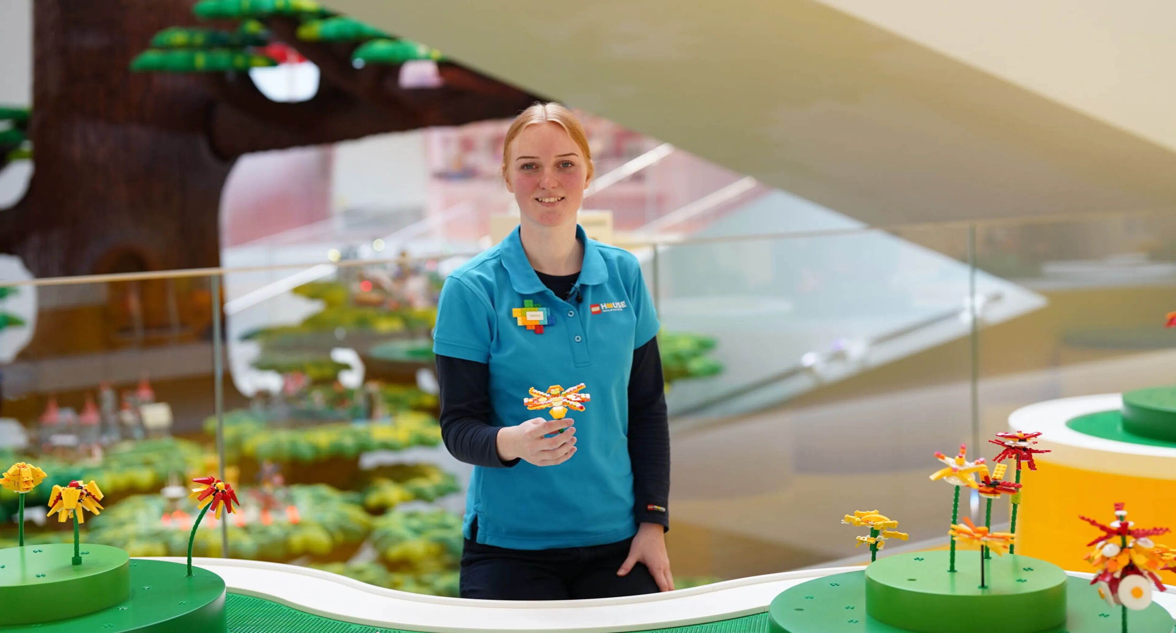 A lego house play agent holds her flower build