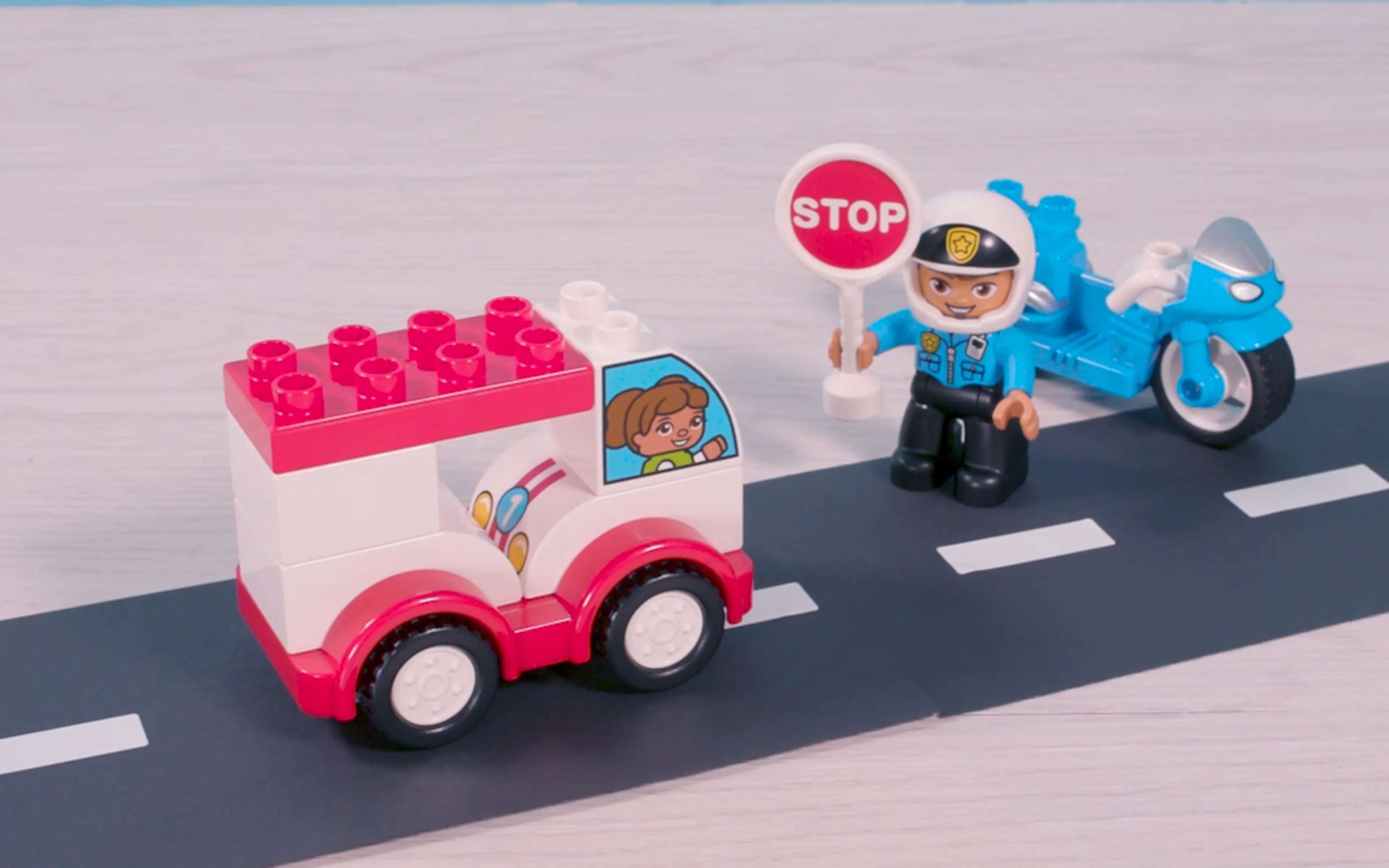 Een afbeelding van een LEGO DUPLO politieagent met een stopbord