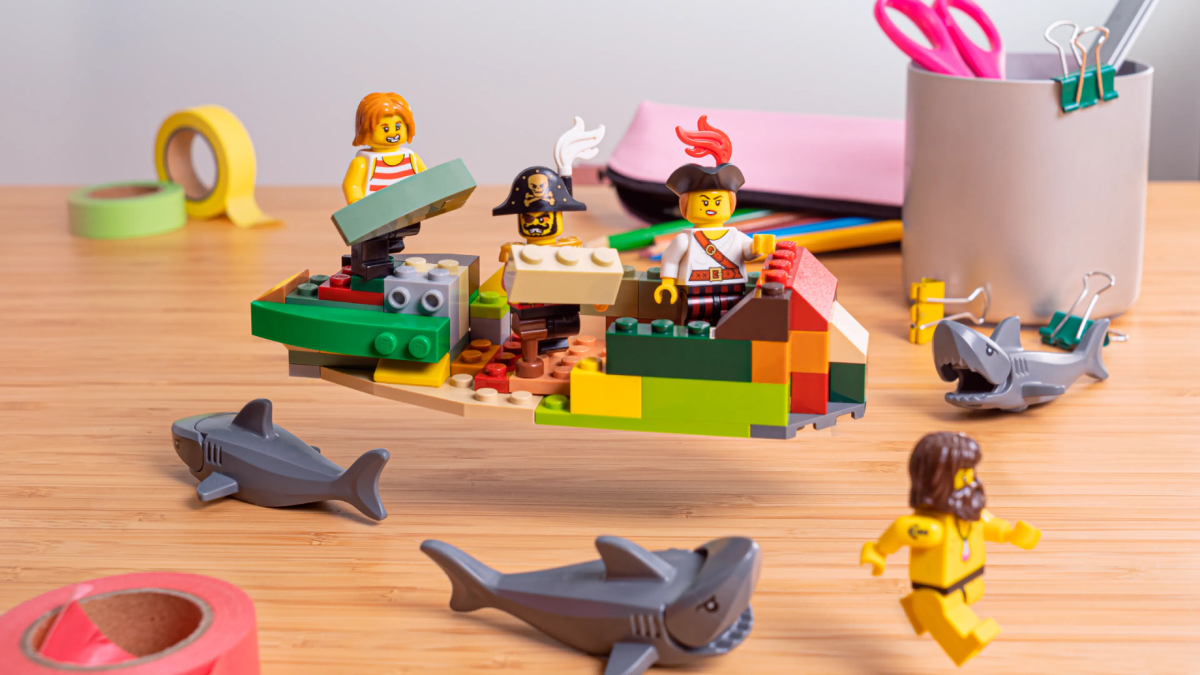 Minifigurer som bygger skeppets sidor, omgivna av hajar