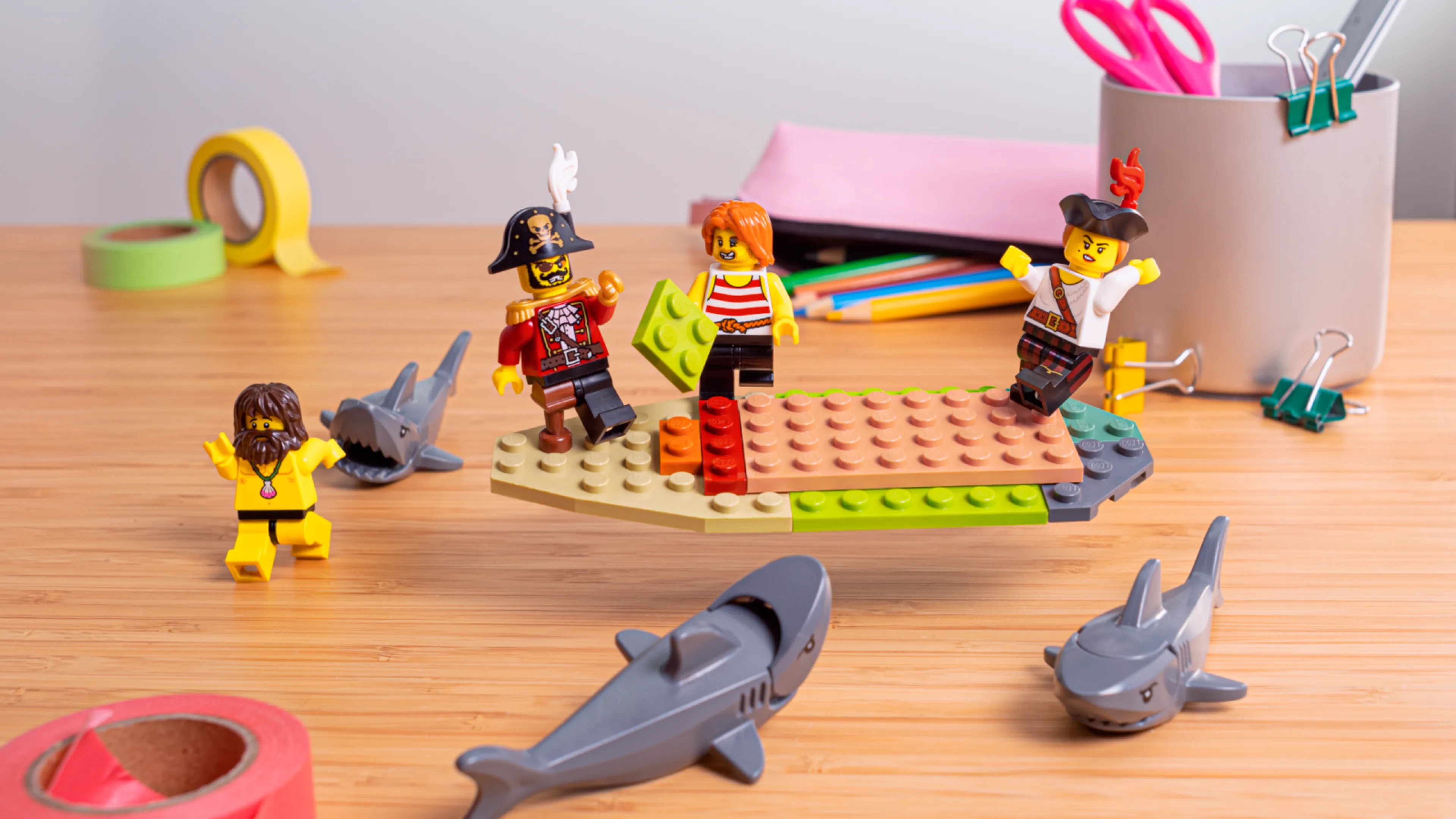 Minifigurer som bygger fartygets underrede, omgivna av hajar