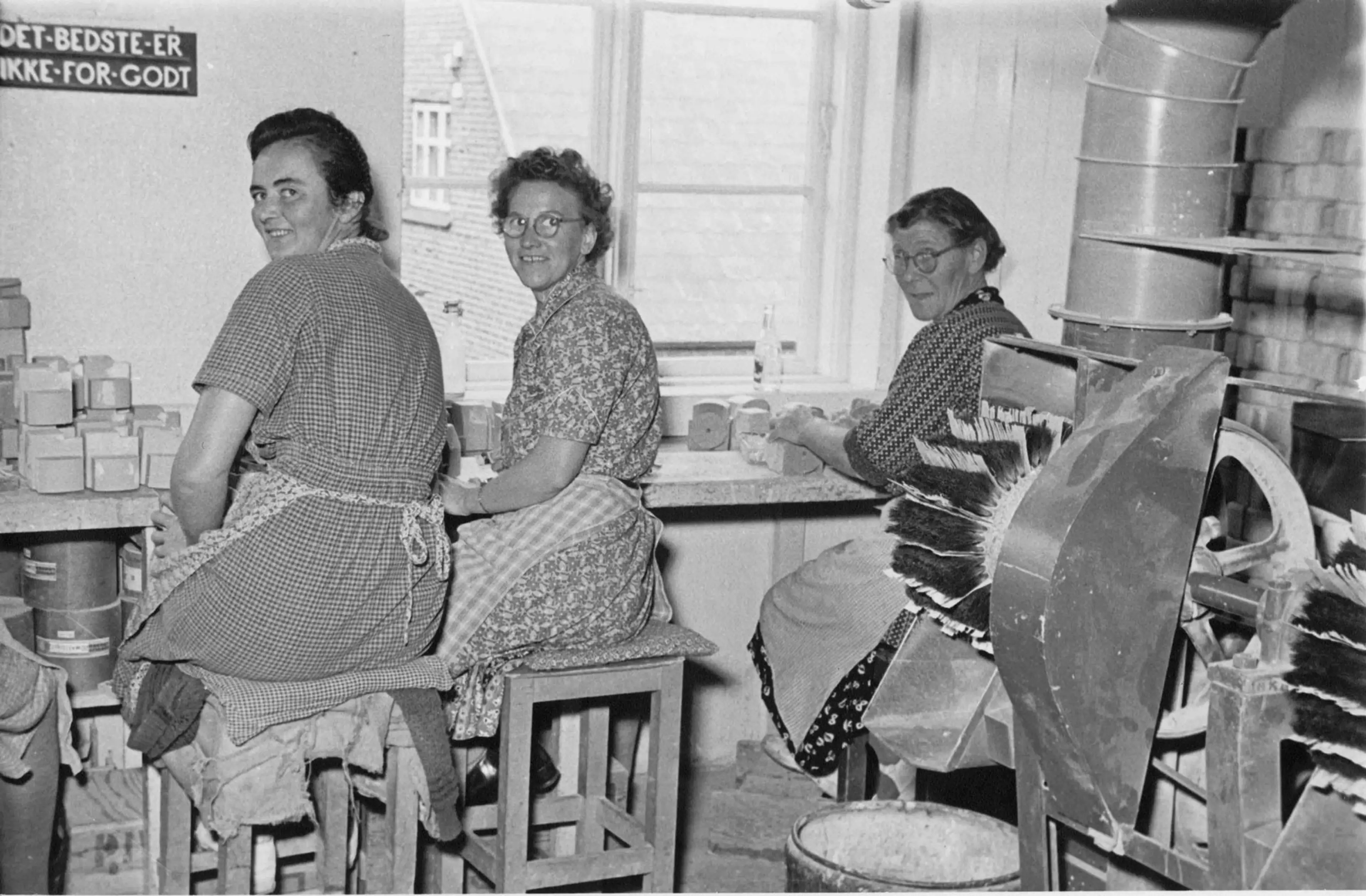 employees in the factory with the company motto on the wall behind them