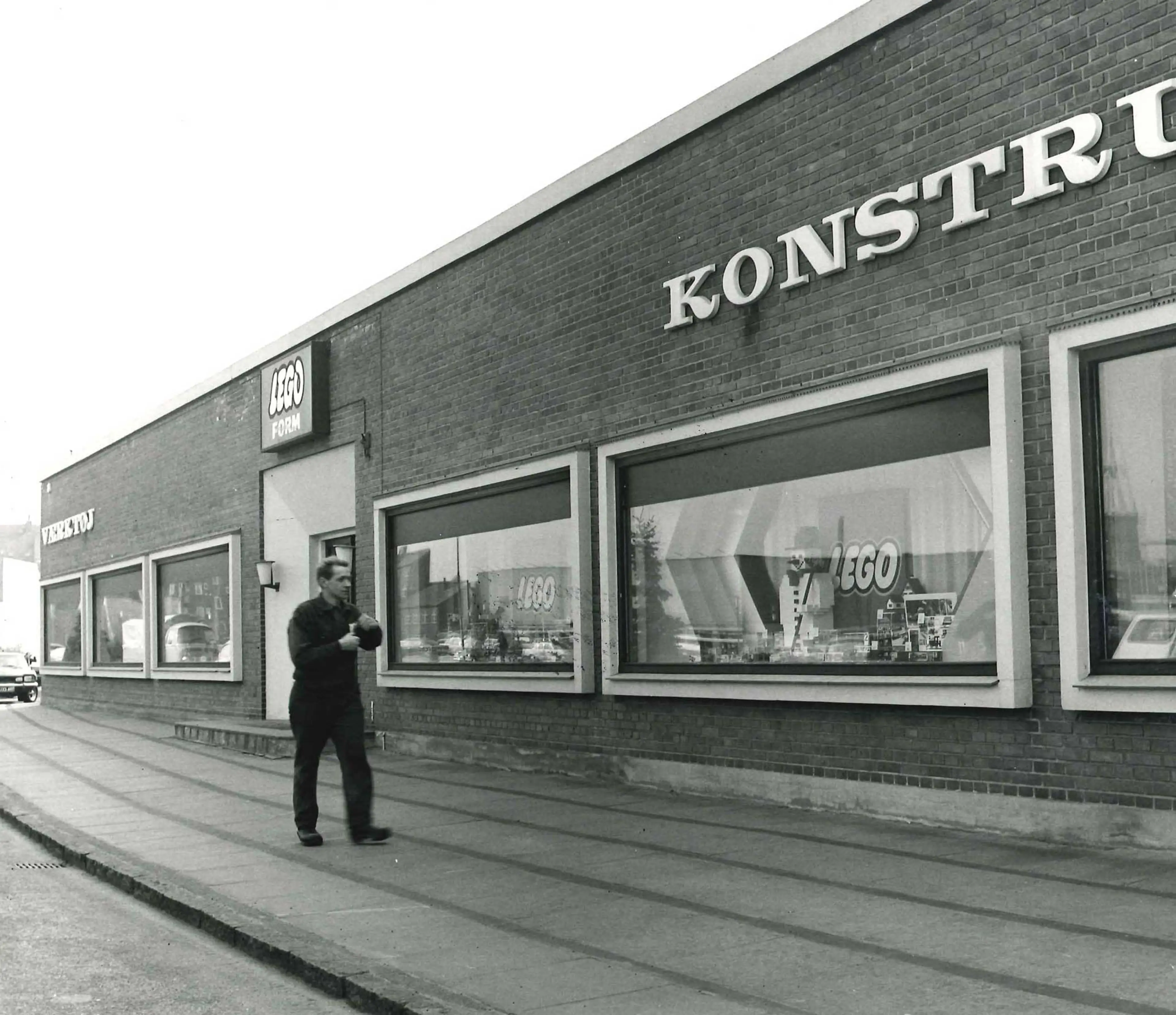 man walking on a sidewalk next to the entrance of LEGO form