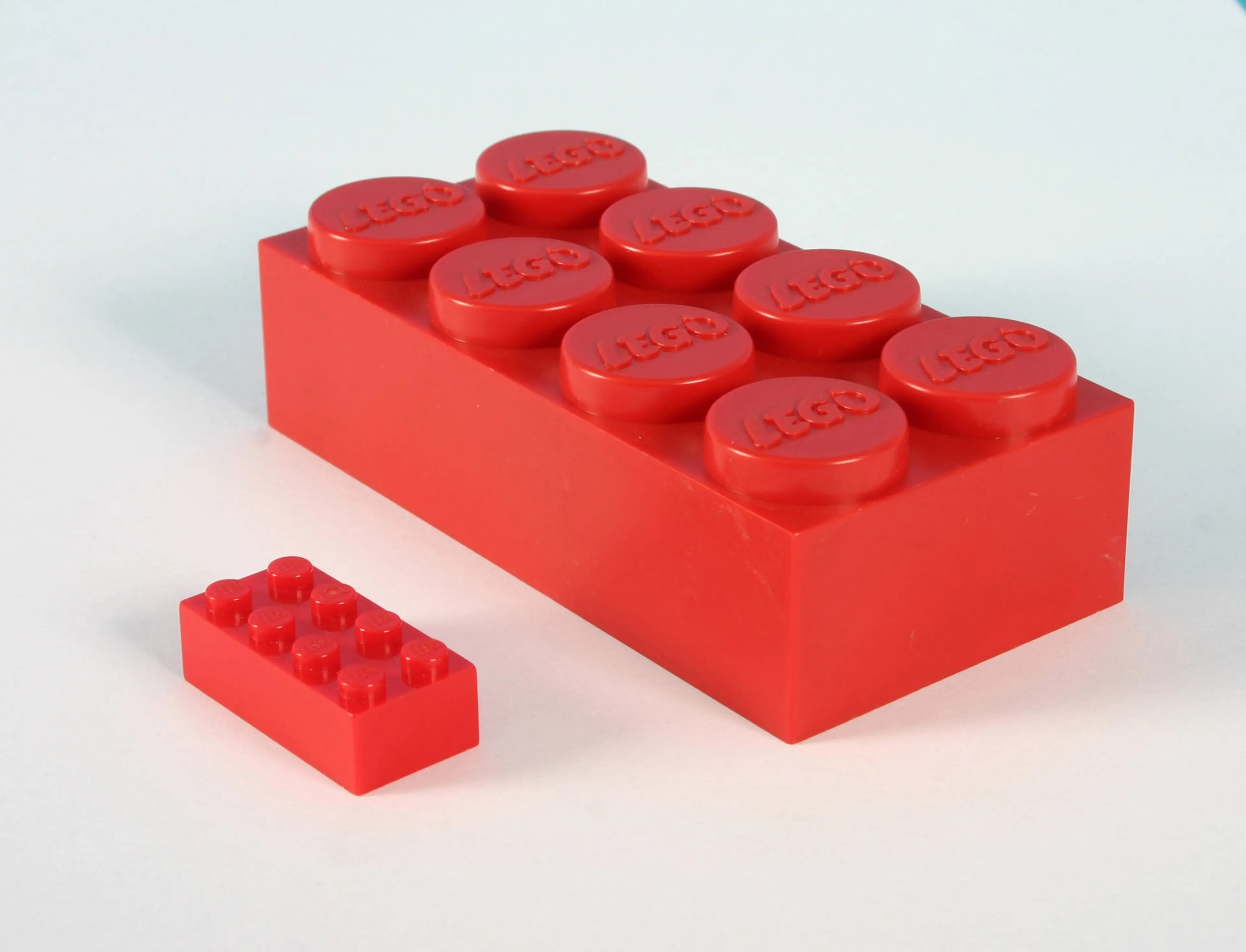 a red LEGO brick next to a red JUMBO brick