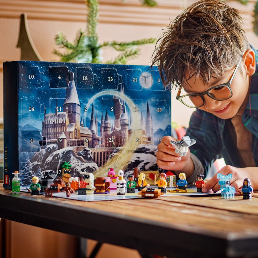 Child playing with the opened LEGO Harry Potter advent calendar and its Hogwarts backdrop