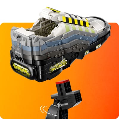 Closeup shot of brick-built Nike Air Max 95 LEGO Set sneaker floating above a rotating display stand against an orange background.