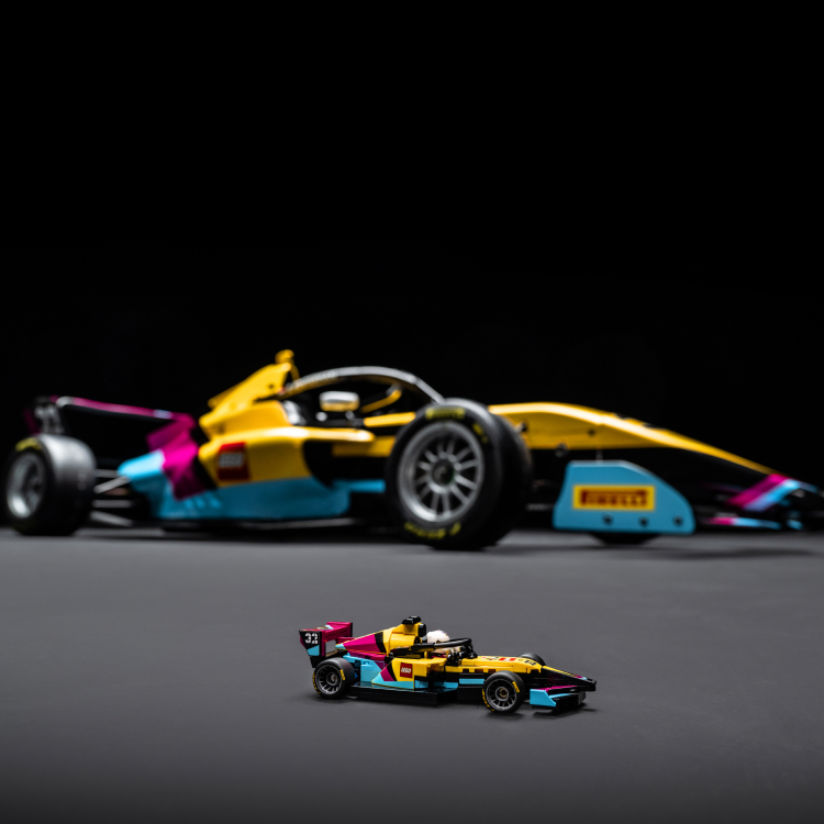 A banner-style image of the LEGO Speed Champions F1 ACADEMY LEGO Race Car, with the real-life car in the background.