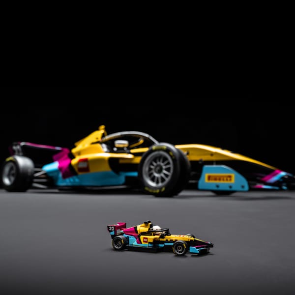 A banner-style image of the LEGO Speed Champions F1 ACADEMY LEGO Race Car, with the real-life car in the background.