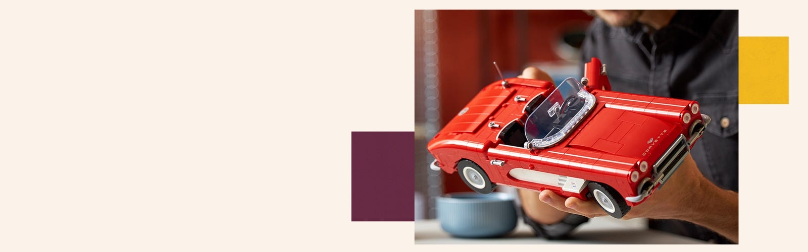 Man holding and inspecting the LEGO Corvette model.