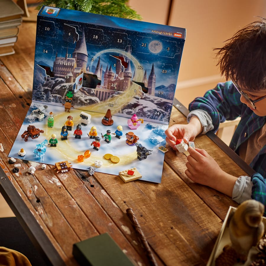 Child building a mini model from the LEGO Harry Potter advent calendar on the playmat