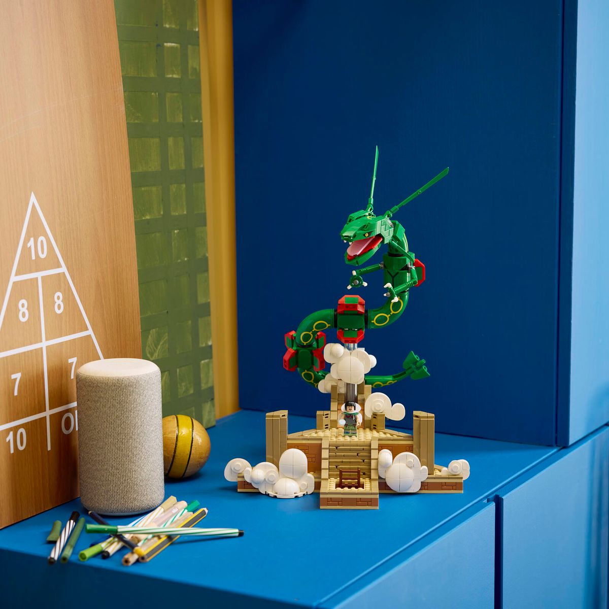 Built LEGO® Pokémon™ Rayquaza displayed on a blue sideboard next to various personal items.