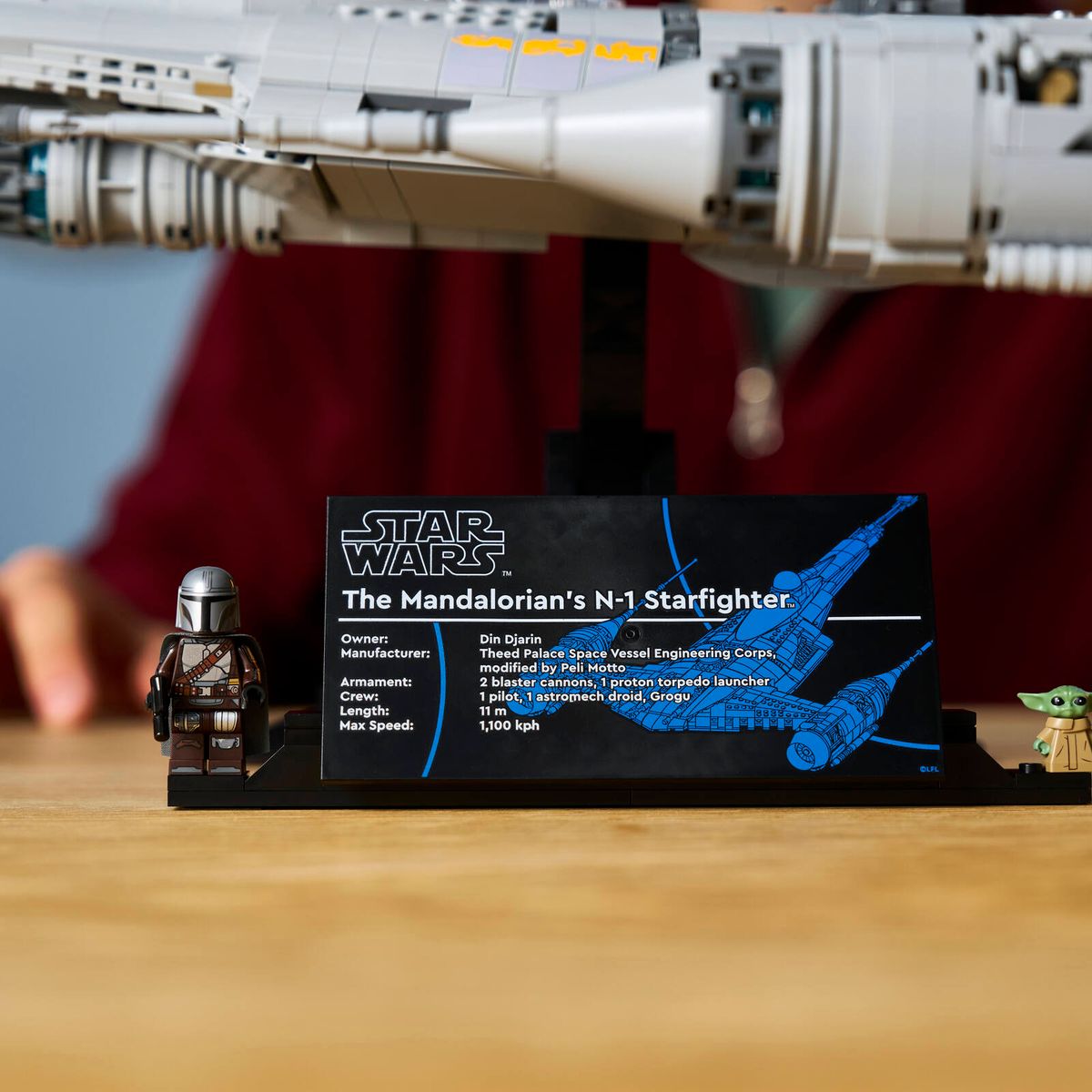 Close-up of information plaque of LEGO® Star Wars™ The Mandalorian's N-1 Starfighter™ with 2 minifigures attached.