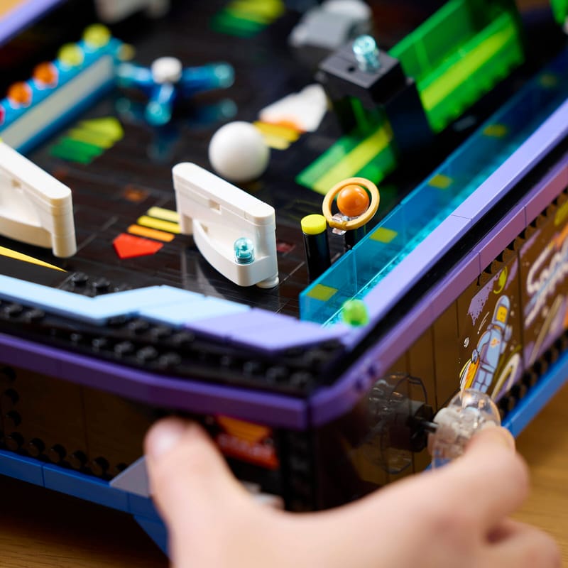 LEGO presenta una máquina de pinball funcional con temática espacial 2 A person using the spring-powered launcher on a LEGO® Icons Arcade Pinball Machine set to play the game.