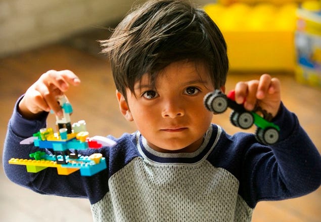 Kind dat twee LEGO Classic creaties vasthoudt