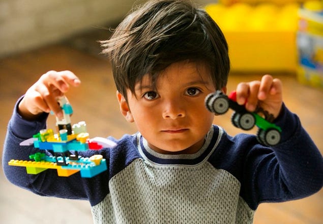 Child holding two LEGO Classic creations