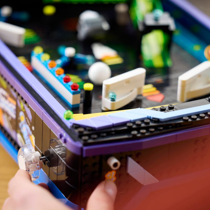LEGO presenta una máquina de pinball funcional con temática espacial 3 A person using the spring-powered launcher on a LEGO® Icons Arcade Pinball Machine set to play the game.
